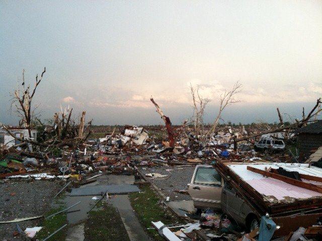 Severe damage in front of empty field, a car has been pancaked by falling debris.
